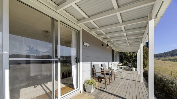 A covered outdoor area with a wooden deck, sliding glass doors, and outdoor furniture. - Towac Cabin 1 • Mt Canobolas Views • Orange (Canobolas)