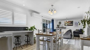A modern kitchen with a dining area, white cabinetry, and a built-in dishwasher.