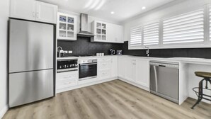 A modern kitchen with white cabinets, stainless steel appliances, and a wooden floor.