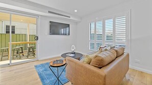 Un salon moderne avec un canapé, une table basse et un coin repas visible à travers des portes vitrées.