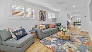Un salon moderne avec un canapé gris, une table basse ronde et un tapis coloré.