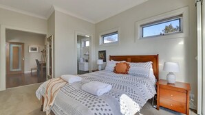 A bedroom with a large bed, a wooden nightstand, and a window.