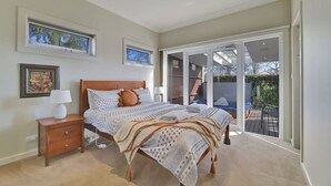 A bedroom with a bed, nightstand, and a view of the outside through a sliding glass door.