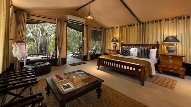 Un dormitorio espacioso con una cama grande, una mesita de noche de madera, un escritorio y vistas al exterior.