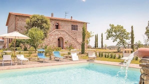 A stone building with a pool, lounge chairs, and a water feature.