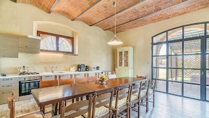 A spacious kitchen with a large island, wooden chairs, and a dining table.