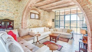 A spacious living room with a high arched brick ceiling, large windows, and a mix of modern and classic furniture.