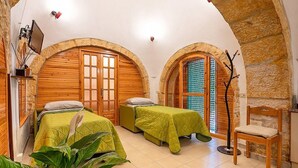A room with two beds, wooden doors, and a stone wall. - Trullo Resia: A cozy and welcoming trullo in the characteristic style of the Apulian countryside, with Free WI-FI. (Ostuni)