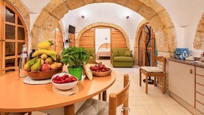 A dining area with a round table, fruit bowls, and a green plant. - Trullo Resia: A cozy and welcoming trullo in the characteristic style of the Apulian countryside, with Free WI-FI. (Ostuni)