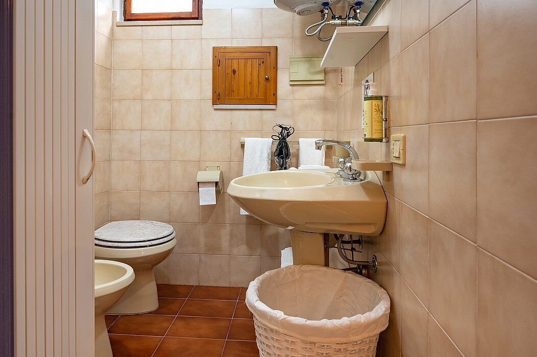 A bathroom with a toilet, sink, and a small trash bin.