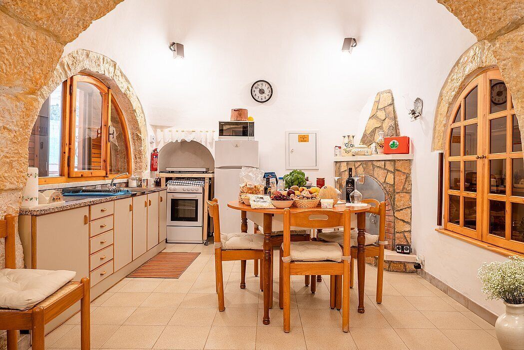 Une cuisine chaleureuse avec des arches en pierre, des meubles en bois et une table à manger dressée pour le repas.