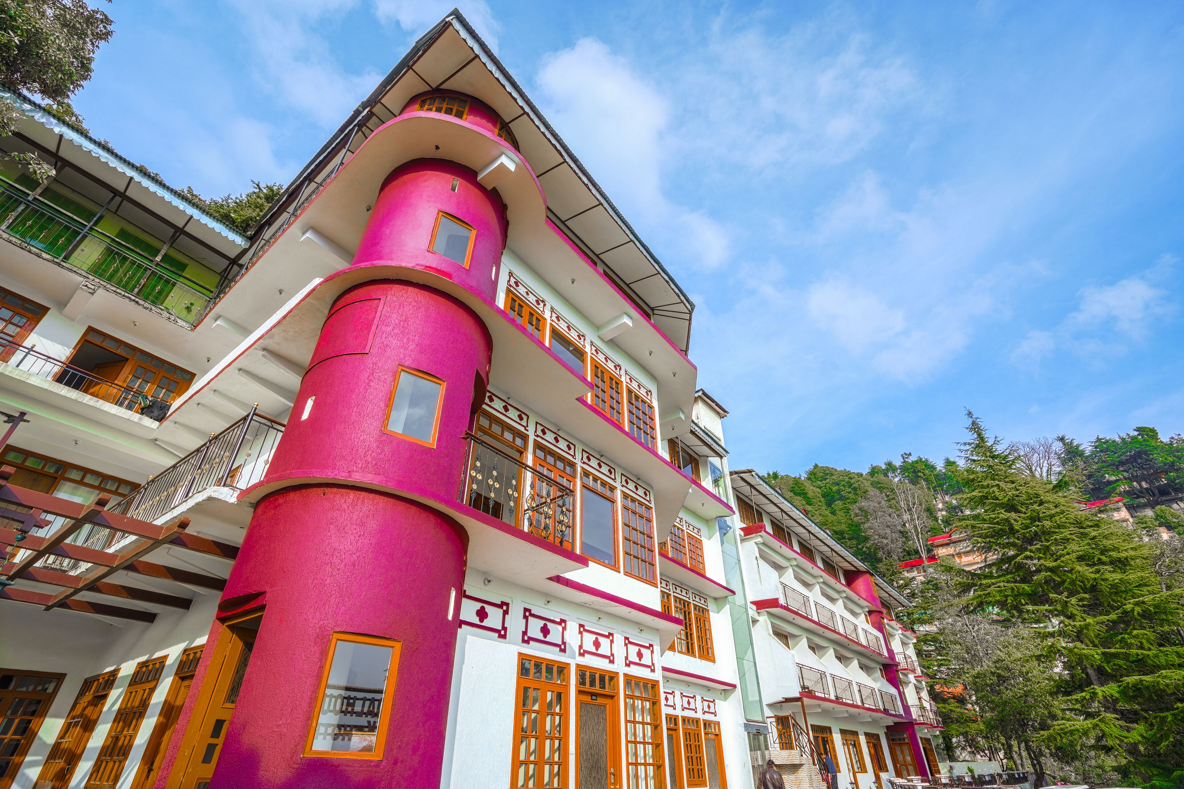 A multi-story building with a distinctive pink and white facade, balconies, and traditional wooden doors.