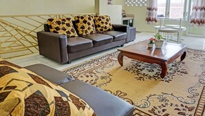 Una sala de estar con sofá, mesa de centro y alfombra estampada.