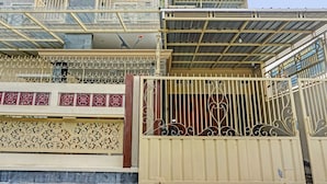 Un edificio de varios pisos con balcón, entrada protegida por una reja y detalles de metal decorativo.