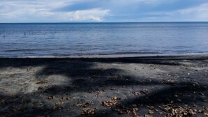 A beach with a sandy foreground and a calm sea under a partly cloudy sky.