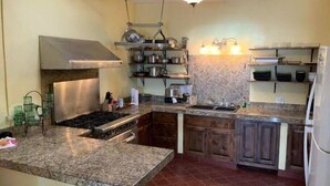 Et køkken med granitbordplader, et rustfrit stål emfang, en loftsvifte og et backsplash.