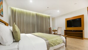 Habitació d'hotel amb llit, televisió penjada a la paret, escriptori i cadira.