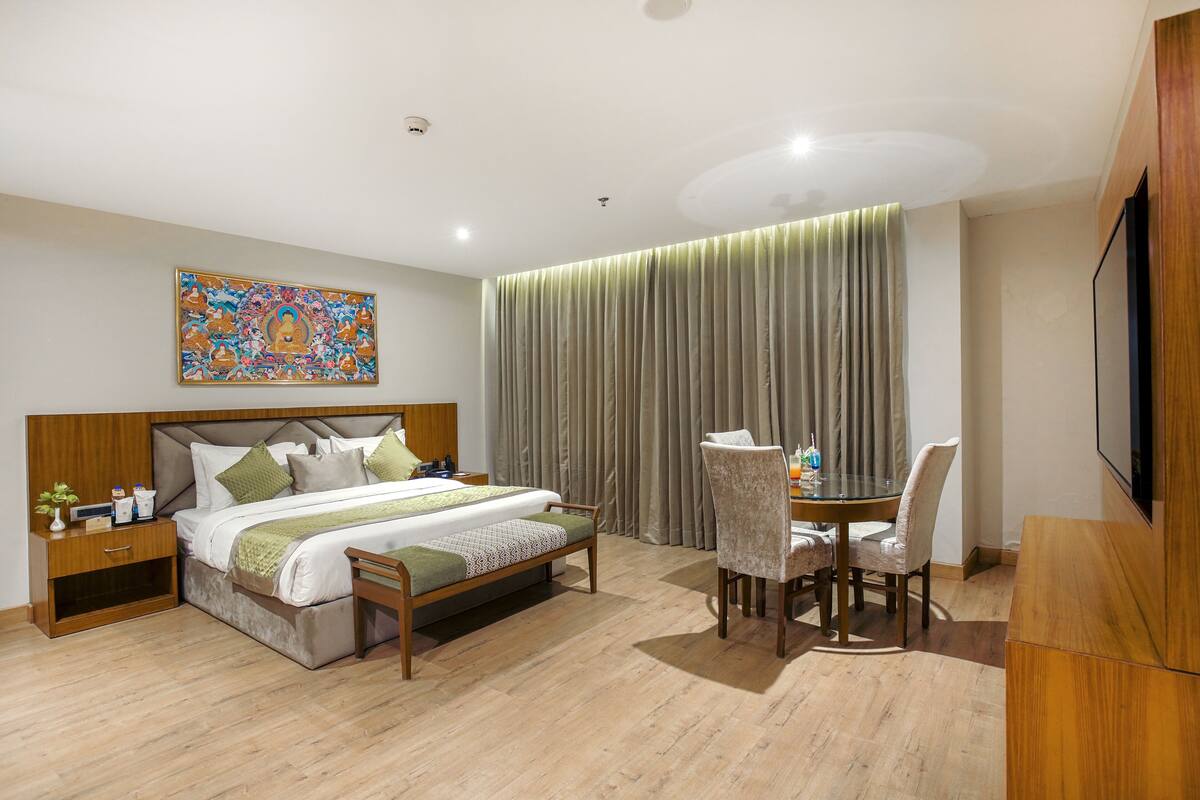A hotel room with a bed, bedside table, lamp, and a television.