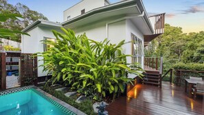 A modern house with a swimming pool, wooden deck, and lush greenery. - Stunning House in peaceful coastal setting (Coolum Beach)