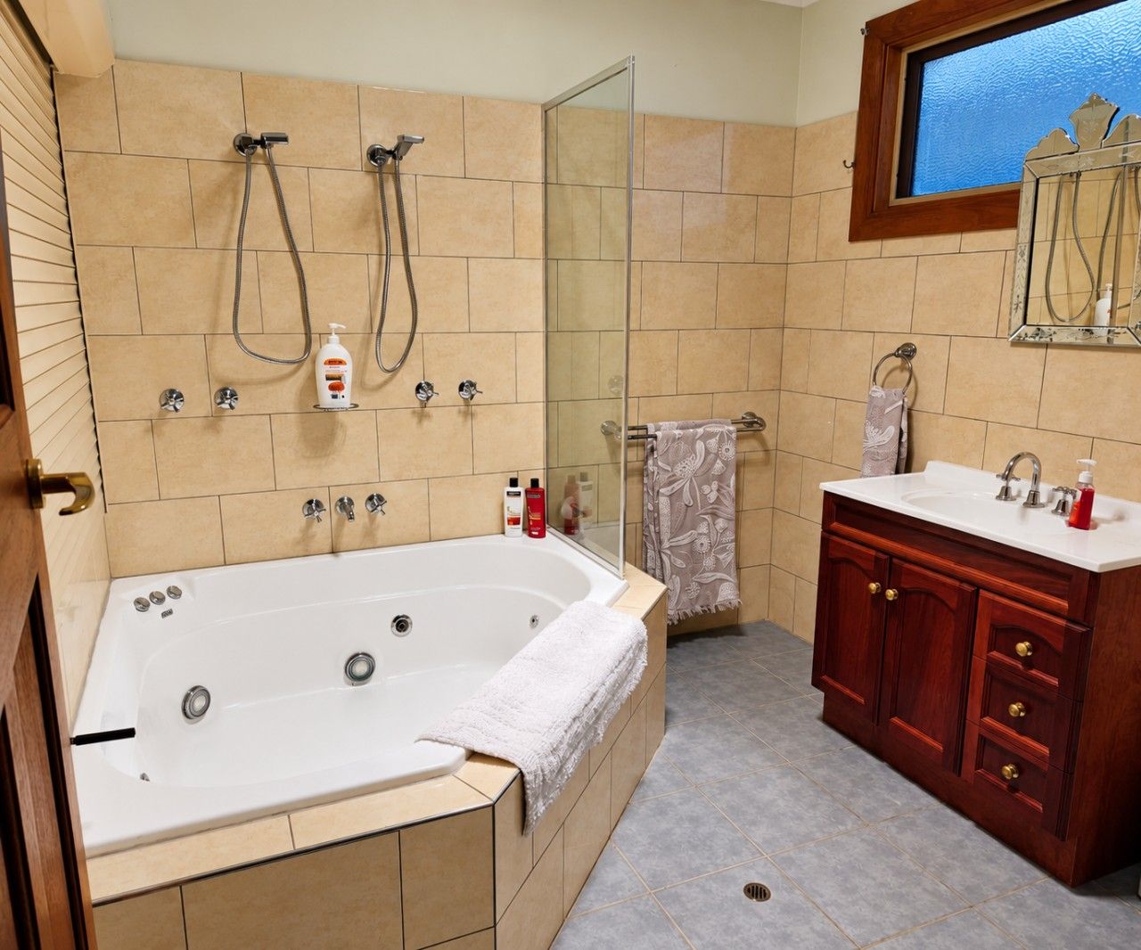 A bathroom with a large bathtub, a vanity with a mirror, and a shower area.