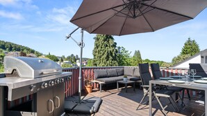A deck with a grill, outdoor furniture, and an umbrella. - Tucan - Rooftop Terrace With View, Bbq, Ps4+streaming (Marburg)