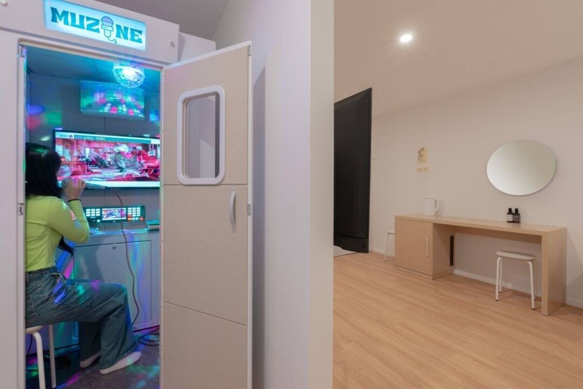Ein Zimmer mit Spielmaschine, Schreibtisch und Spiegel.