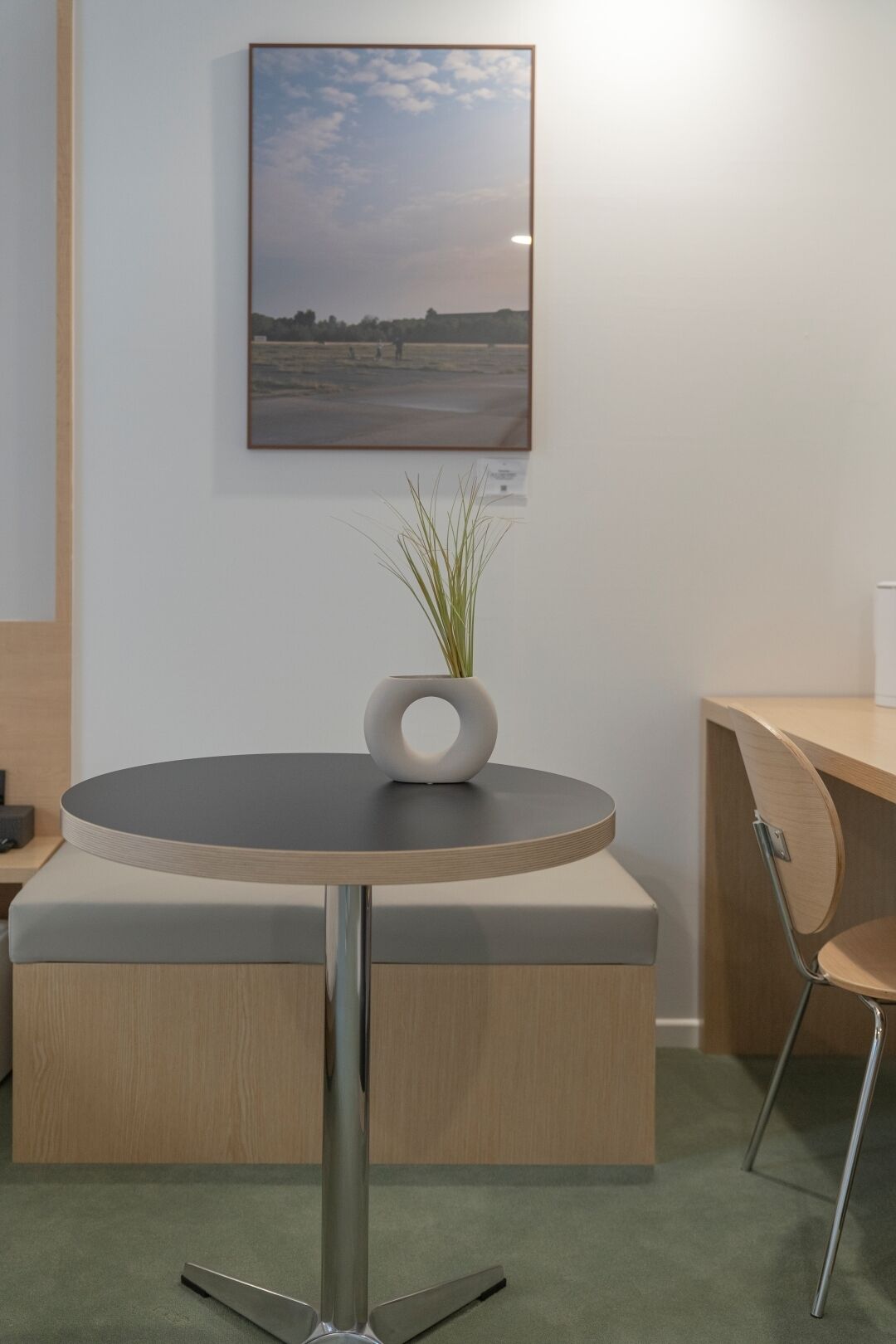 A modern, minimalist room with a round table, a chair, and a small potted plant.