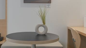 A modern, minimalist room with a round table, a chair, and a small potted plant.