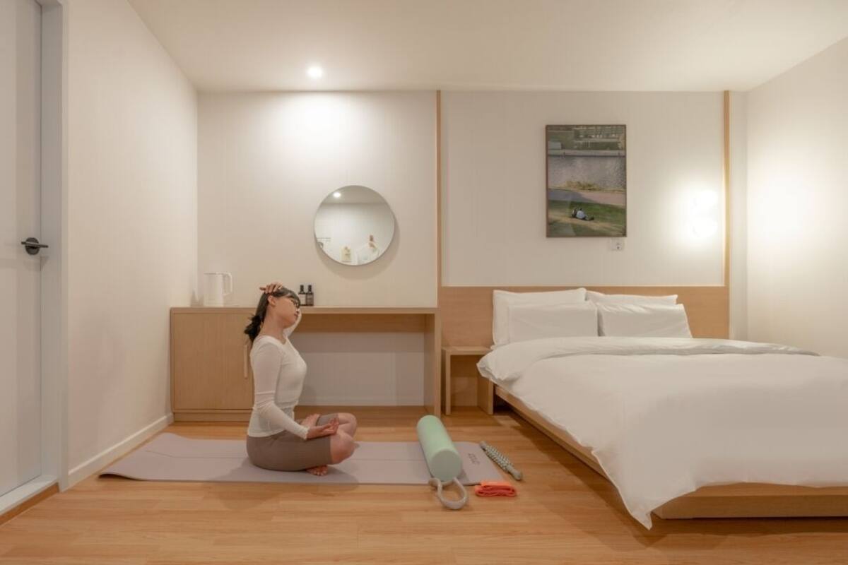 Ein Hotelzimmer mit Bett, Yogamatte, Yoga-Block und einem kleinen Tisch mit Spiegel und Pflegeprodukten.