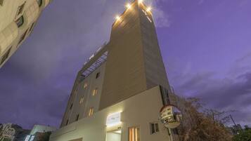 A tall building with a modern architectural design, featuring a prominent entrance and a visible sign.