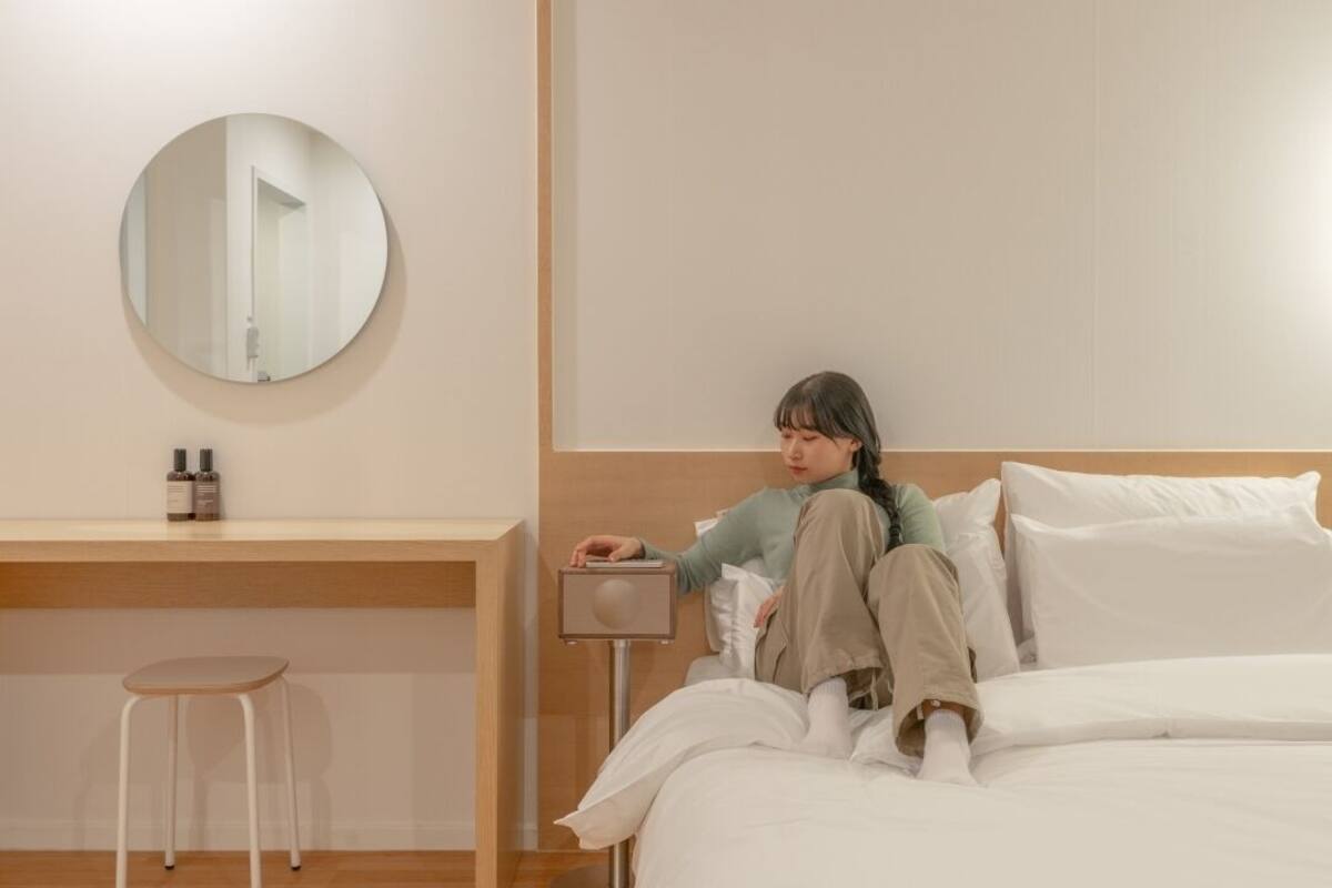 Ein Schlafzimmer mit Bett, Nachttisch, Stuhl und rundem Spiegel an der Wand.