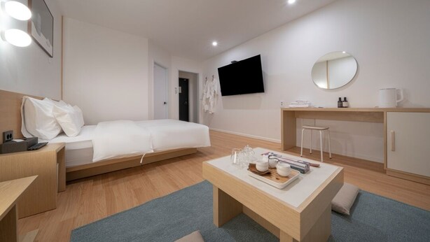 Una moderna camera d'albergo con un letto, una scrivania, una TV e uno specchio.