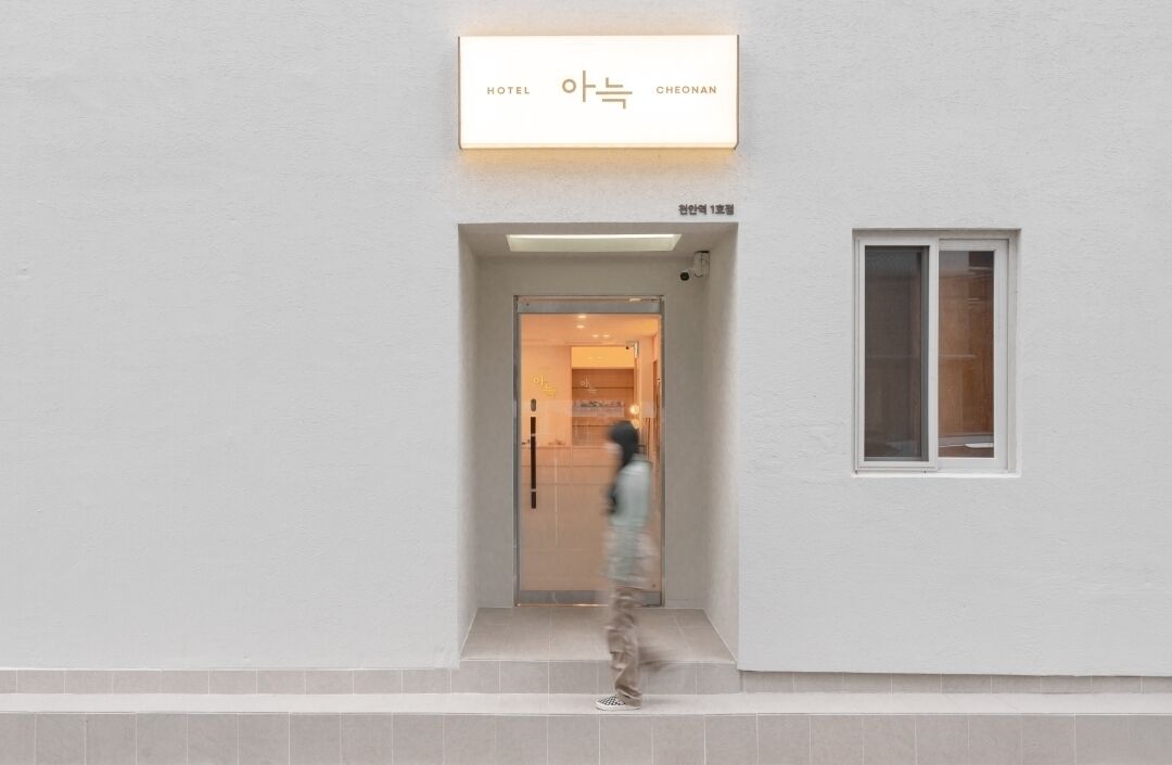 Entrada de un hotel con un cartel que dice "HOTEL CHEONAN" y una puerta a la vista.