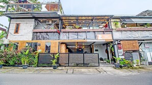 Een meerhoog gebouw met een overdekt terras, een garage en verschillende planten in potten.