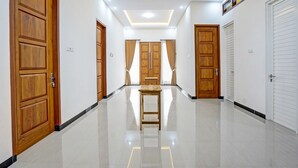A hallway with wooden doors, a marble floor, and recessed ceiling lighting. - OYO Ipeda Family Residence 2 (Banyuwangi)