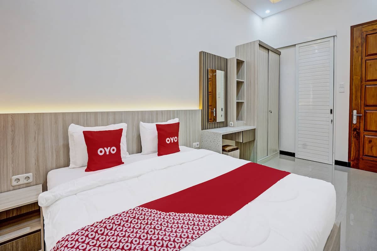 A modern hotel room with a large bed, a vanity with a mirror, and a wardrobe.