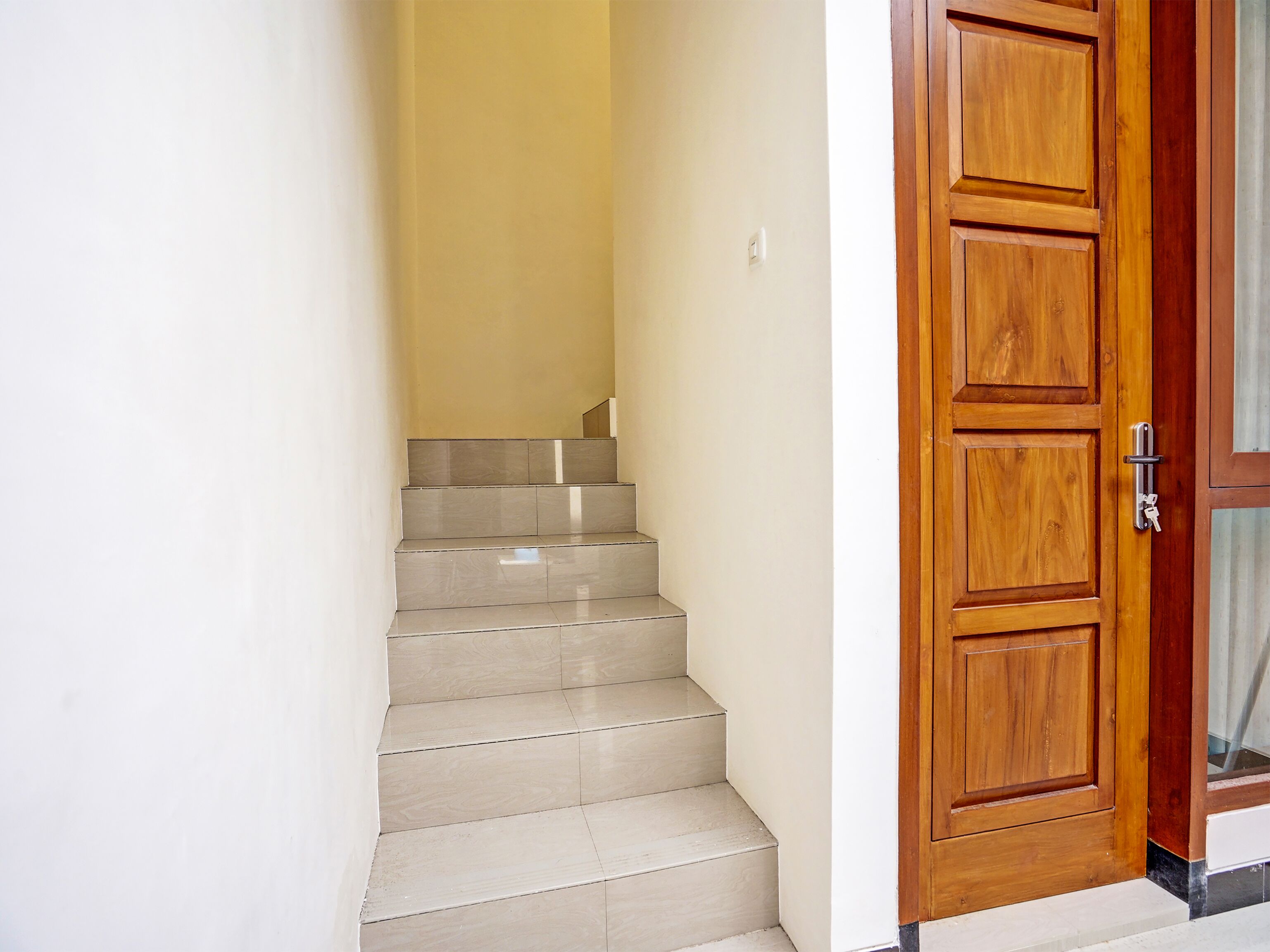 A set of beige tiled stairs leading to a wooden door with a metal handle.