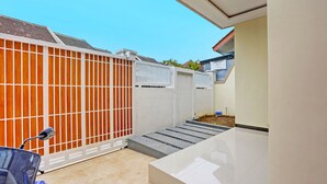 A modern outdoor area with a tiled floor, a white gate, and a blue scooter. - OYO Ipeda Family Residence 2 (Banyuwangi)