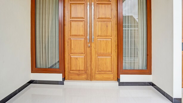A wooden double door with a sliding glass panel on each side, set in a corner with a tiled floor. - OYO Ipeda Family Residence 2 (Banyuwangi)