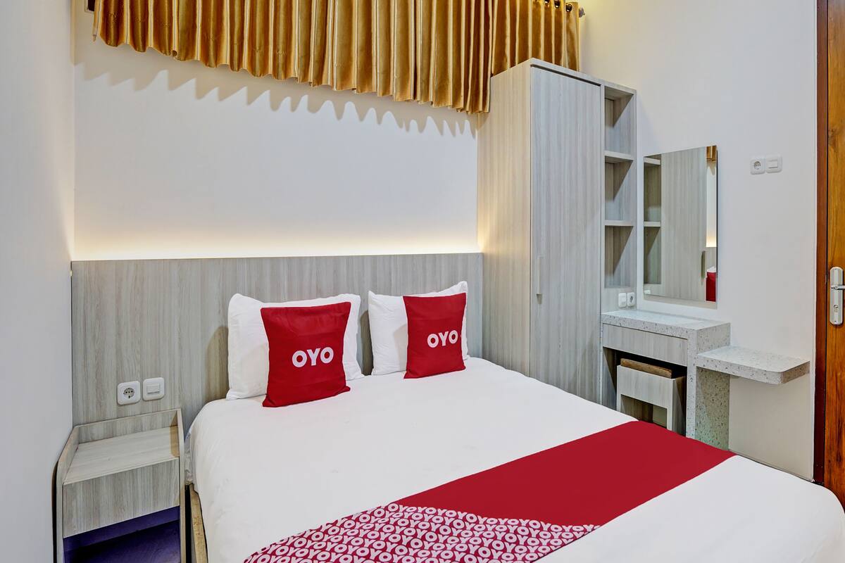 A hotel room with a bed, a bedside table, a wardrobe, and a mirror.