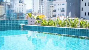 Una piscina con azulejos azules y plantas verdes al frente.