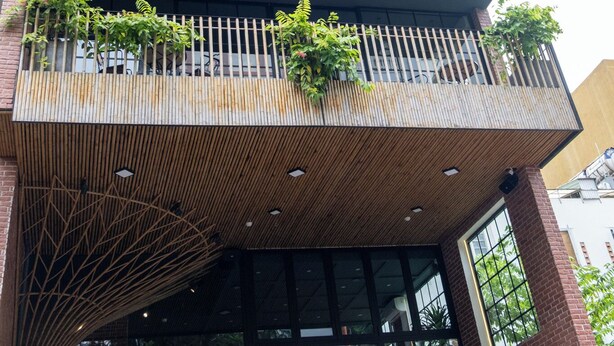 Un edificio de varios pisos con balcones, ventanas amplias y vegetación.