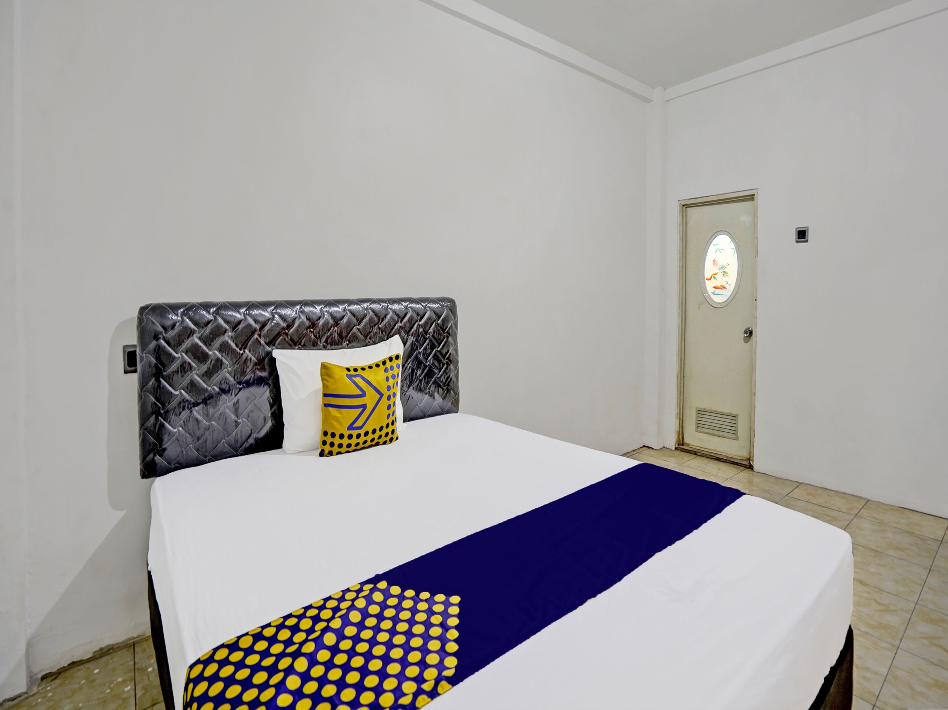 A hotel room with a bed, a door, and a wall.