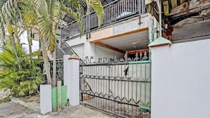 A gated entrance with a metal gate, a white wall, and a balcony with a metal railing.