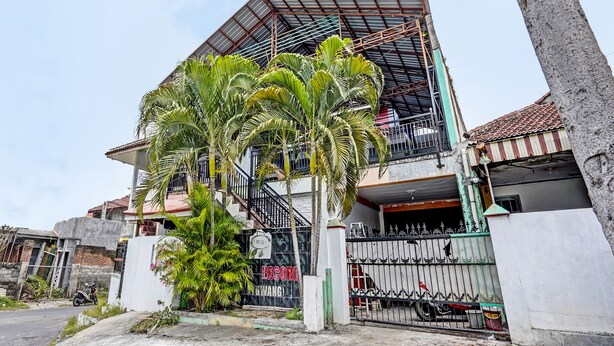 A modern two-story house with a sloped roof, a gated entrance, and a small balcony.