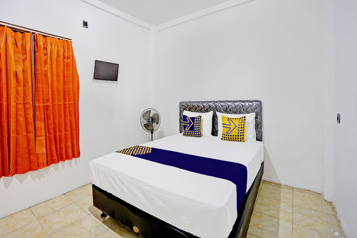 Une chambre à coucher avec un lit, un ventilateur et des rideaux orange.