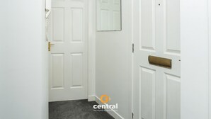 A hallway with white doors, a mirror, and a carpeted floor.