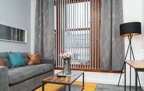 A modern living room with a grey sofa, a wooden coffee table, and a black floor lamp.