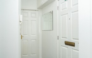 A hallway with white doors, a mirror, and a carpeted floor.