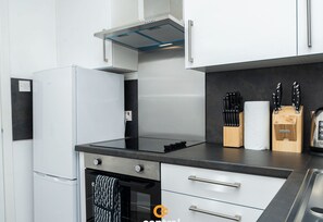 A modern kitchen with a built-in oven, a stainless steel range hood, and a countertop with knives and a toaster.